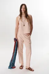 Pantalón de lino stretch color rosa pálido, de corte recto y tiro medio, con costuras visibles en color marrón oscuro.