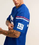 Remera deportiva azul con tecnología Dry, cuello en V, manga corta con estampado lettering y rayas contrastantes, estampado lettering NFL Giants.