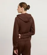 Campera deportiva con capucha ajustable, cierre frontal por cremallera, mangas largas con sisa raglán y puños ajustados. Presenta bolsillo tipo canguro y cordones con lettering estampado.