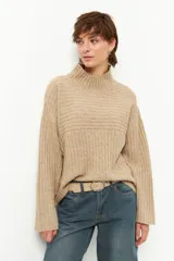 Polera color beige de tejido tramado, cuello alto y mangas holgadas.