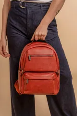 Mochila de cuero sintético color negro con textura granulada. Cuenta con un compartimento principal con cierre, un bolsillo frontal con cierre, correas ajustables y asa superior.