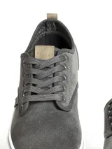 Zapatillas casuales de caña baja, color negro, con capellada de textil y suela de PVC blanca. Presentan cordones negros y detalles en cuero sintético marrón en la lengüeta.