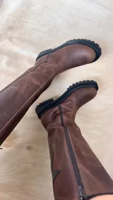 Botas altas de cuero en color beige y marrón tostado, con suela track chunky y detalle de estrella blanca grande en el lateral de la caña.