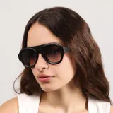 Lentes de sol con armazón de acetato negro y diseño de puente plano, estilo aviador moderno con cristales oscuros.