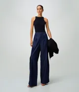 Pantalón wide leg de jean azul oscuro, de talle alto con pretina estructurada, pinzas frontales, sobreposición cruzada y piernas amplias.