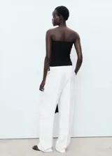 Pantalón de traje tiro medio, color blanco, de diseño recto y largo, con cierre delantero de botón, gancho y cremallera, detalle de pinzas y dos bolsillos laterales.
