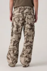 Pantalón cargo de corte amplio con estampado de camuflaje en tonos beige, marrón y verde. Cuenta con cintura elástica ajustable con cordón, bolsillos laterales con solapa y bolsillos traseros.