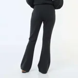 Pantalón de corte flare y tiro medio, confeccionado en felpa ligera de color negro. Presenta una costura vertical central en el frente de cada pierna y un diseño de calce fluido.
