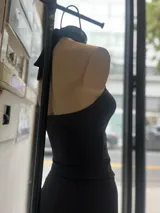 Top negro de cuello halter con abertura frontal tipo cut-out y detalle de herraje metálico en forma de V. Confeccionado en tejido elástico ajustado al cuerpo.