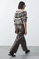 Pantalón de cuero sintético con fit barrel, de silueta amplia con volumen en las piernas y botamanga levemente entallada. Presenta bolsillos laterales y cierre frontal.
