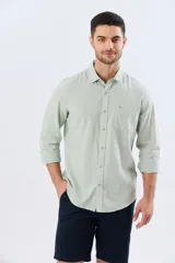 Camisa de lino de manga larga en color beige, con cuello camisero, cierre frontal de botones y un bolsillo ojal en el pecho.