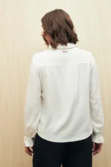 Camisa verde clara de manga larga confeccionada en viscosa ligera, con cuello clásico, cierre frontal con botones, detalles calados en la parte superior y pequeños volados.