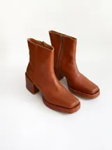 Bota de caña media color óxido, confeccionada en cuero, con plataforma y taco cuadrado texturizado, punta cuadrada y cierre lateral.