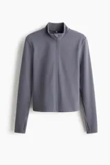 Campera deportiva gris de corte ajustado con cuello elevado, cierre frontal completo y mangas largas con abertura para el pulgar.