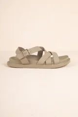 Sandalia baja color beige topo, con tiras anchas cruzadas en el empeine y tira de ajuste con hebilla metálica en el tobillo. Posee una plataforma gruesa y suela de goma.