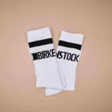 Medias de caña media color blanco con una franja horizontal negra y el texto 'STOCK' estampado en negro en la parte superior.