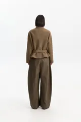 Chaqueta corta de silueta amplia confeccionada en mezcla de lana, poliéster y acrílico. Presenta cuello alto estructurado, cierre frontal con alamares y cinto ajustable que define la cintura. Incluye mangas largas con trabas abotonadas en los puños.