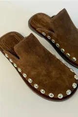Sueco de gamuza color marrón con detalle de tachas metálicas doradas alrededor de la suela y punta redonda.