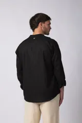 Camisa de manga larga confeccionada en lino, con cuello mao y cierre frontal de botones. Presenta un corte relajado y diseño minimalista.