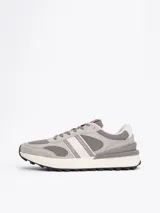 Zapatillas Tommy Jeans grises de corte bajo, con exterior de ante y malla, detalles distintivos de la marca, suela de goma dentada y cierre con cordones.