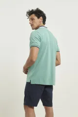 Chomba de piqué azul con cuello clásico, mangas cortas y corte recto. El cuello y los puños tienen detalles a contratono en azul marino y blanco.