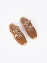 Slide estilo alpargata confeccionado en cuero descarne color celeste, con cordones beige, detalles de flecos y dijes colgantes, sobre una base de yute trenzado.