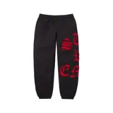 Pantalón de jogging negro con diseño de letras recortadas en color rojo en la pierna izquierda. Cuenta con cintura elástica y puños en los tobillos.
