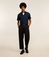 Camisa de manga corta con cuello inglés y cierre frontal abotonado, confeccionada en una mezcla de fibras de bambú, viscosa, poliéster y elastano. Presenta un diseño liso y entallado.