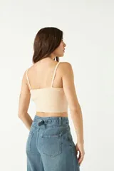 Top tejido de punto color beige, con escote corazón y breteles finos. Presenta una textura acanalada y un corte corto al cuerpo.