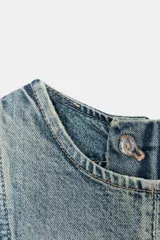 Vestido corto de denim con cuello redondo y manga sisa. Presenta costuras inclinadas y un bajo asimétrico. Cierre con cremallera en la espalda.