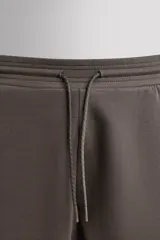 Pantalón jogger relaxed fit Zara Athleticz de tejido técnico compacto elástico con mezcla de algodón. Presenta cintura elástica ajustable con cordón, bolsillos laterales en la cadera, bolsillo trasero con cierre de cremallera, bajo ajustable con elástico y detalle de logo estampado en la pernera.