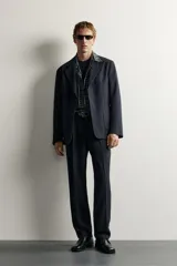 Blazer de corte relaxed fit con cuello de solapas de muesca y cierre frontal de un botón. Cuenta con bolsillos de plastrón en la cadera y mangas largas.