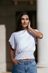 Top blanco de corte holgado con mangas cortas tipo murciélago y detalle de frunce con encaje en la cintura.
