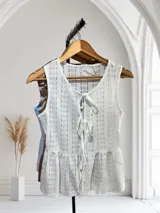 Blusa sin mangas de encaje con detalle de lazo en el escote y corte peplum.