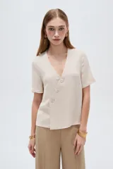 Blusa marrón de manga corta con cuello en V y cierre frontal cruzado con tres botones.