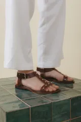 Sandalias negras de cuero con tiras finas, pulsera al tobillo con hebilla metálica y apliques de tachas plateadas.