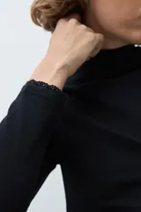 Remera de manga larga con detalle de puntilla en los puños, confeccionada en tejido suave y elástico.