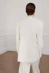 Blazer cruzado Zara Woman Collection confeccionado en hilatura de viscosa, de color blanco. Presenta cuello alto, manga larga con abertura y botones, bolsillos delanteros y cierre frontal cruzado con botones.