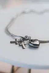Pulsera de cadena tipo serpiente en color plateado, con dijes colgantes de dos cruces y un corazón grabado con la palabra 'MUM'.