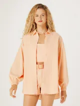 Camisa oversize color naranja con cuello clásico y mangas largas con puños elásticos.