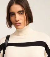 Vestido midi de punto con cuello alto y mangas largas. Diseño recto con rayas horizontales negras sobre fondo crudo y aberturas laterales.