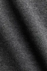 Cárdigan corto de punto fino color gris, con cuello desmontable de pelo sintético color beige. Presenta cierre frontal con botones y terminaciones acanaladas en puños y bajo.