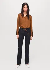 Camisa de corte recto con acabado satinado, cuello camisero clásico, cierre frontal con botones y mangas largas con puños abotonados.