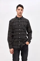 Camisa de corte regular fit, confeccionada en tela de algodón con diseño de cuadros en tonos marrones y negros. Presenta cuello clásico, cierre frontal con botones personalizados y un bolsillo en el pecho con el logo de la marca bordado.