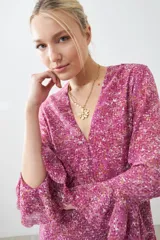 Vestido corto fucsia con estampado floral, escote en V, mangas largas con volados y falda acampanada con volados en el ruedo.