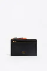 Billetera de estructura blanda confeccionada en nylon negro, con cierre de cremallera superior y bolsillo frontal con cierre. Presenta logo metálico dorado en el frente y tirador de cordón decorativo.