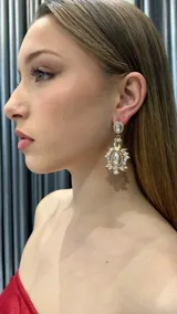 Aros colgantes dorados con incrustaciones de strass y cristales transparentes de diferentes tamaños.