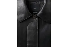 Chaqueta de cuero sintético negro con solapas clásicas, cierre frontal de botones ocultos y mangas largas amplias.