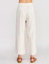 Pantalón palazzo de tiro alto color beige, confeccionado en mezcla de lino y viscosa, con silueta suelta y fluida, cintura elastizada, bolsillos delanteros aplicados y ruedo festoneado de corte tobillero.