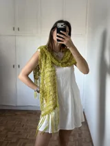 Pashmina tejida a mano con hilado fantasía en color verde oliva, con diseño de red y flecos en los extremos.